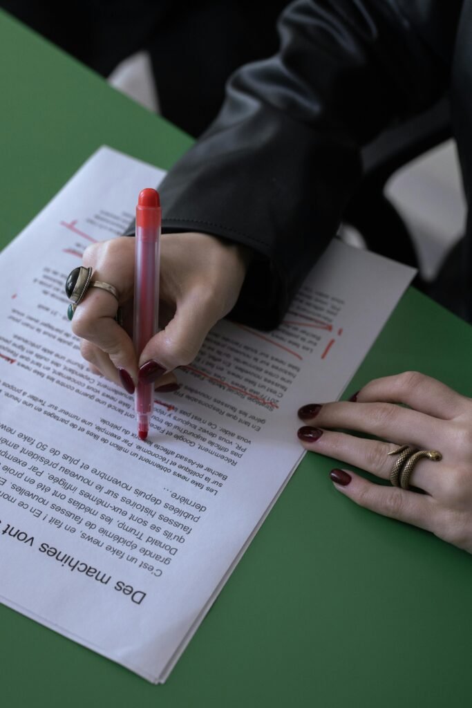 Close-up of an editor’s hand marking corrections on a printed manuscript with a pen.