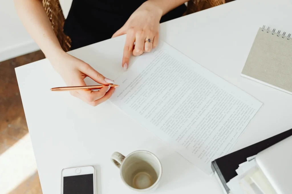 Close-up of a professional reviewing a printed document with a pen at a white desk