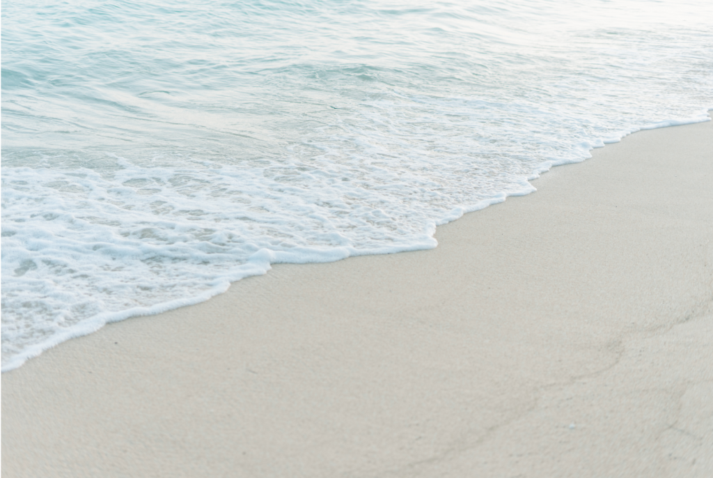 Gentle waves washing onto pale sand at low tide, symbolizing clarity and a calm, steady editorial process.