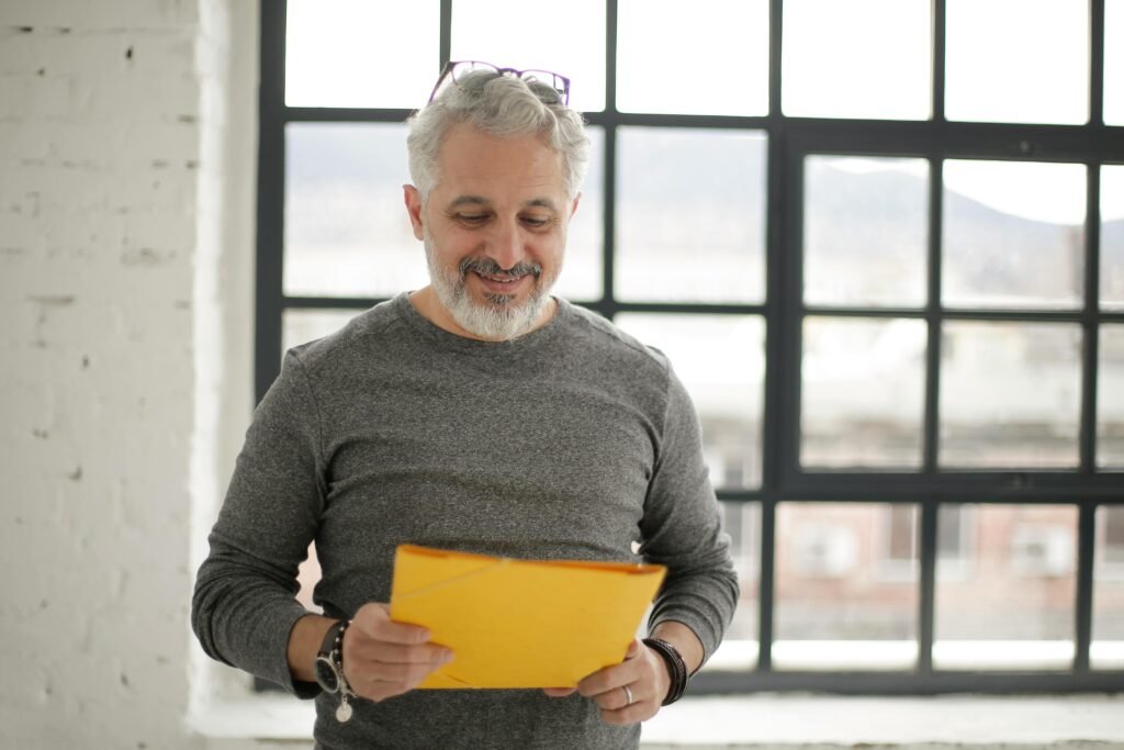 Man reading a yellow folder, smiling with relief. Visual metaphor for the clarity and confidence that come from editing support.